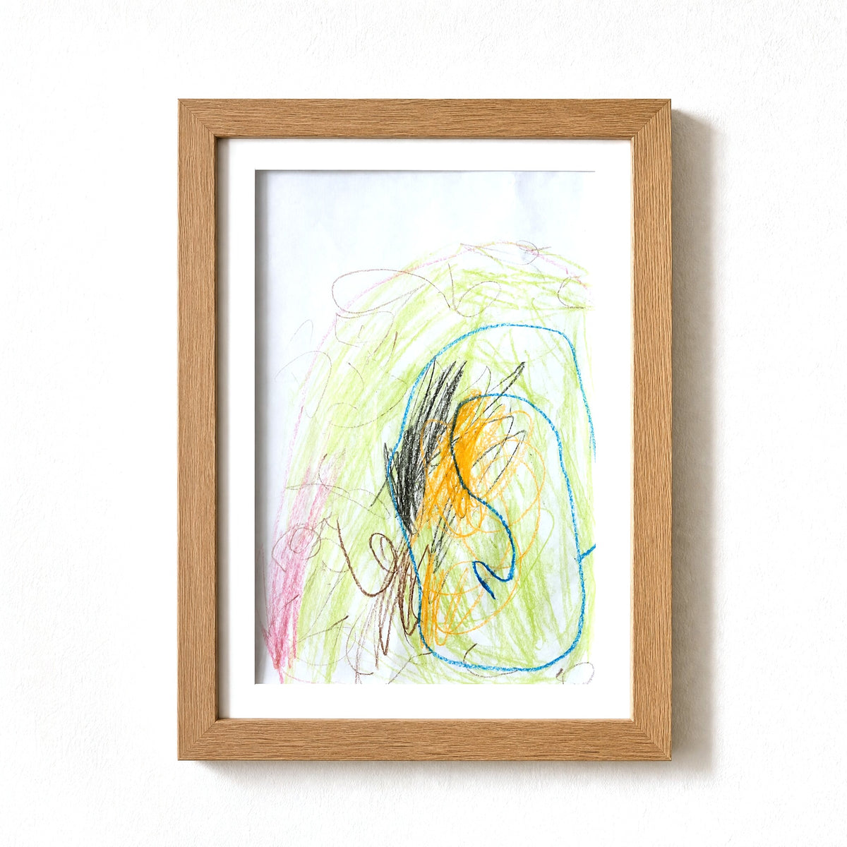 PeekDoodle art frame in natural wood on a wall, holding a child's crayon drawing